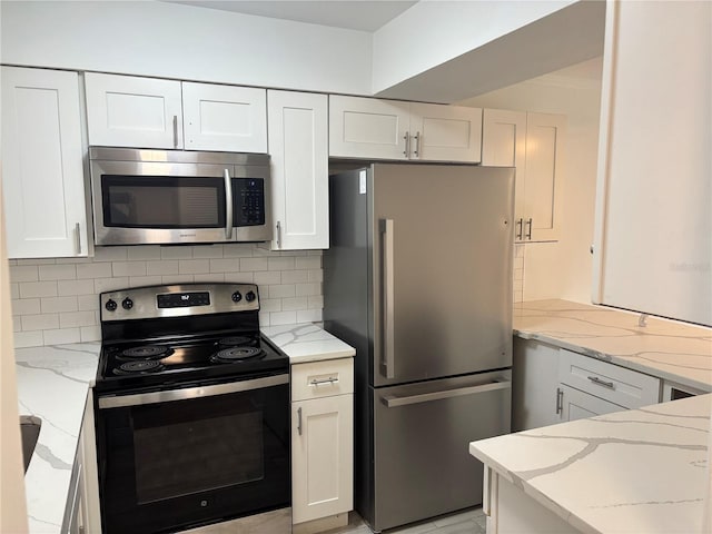 kitchen with white cabinets, backsplash, light stone counters, and appliances with stainless steel finishes