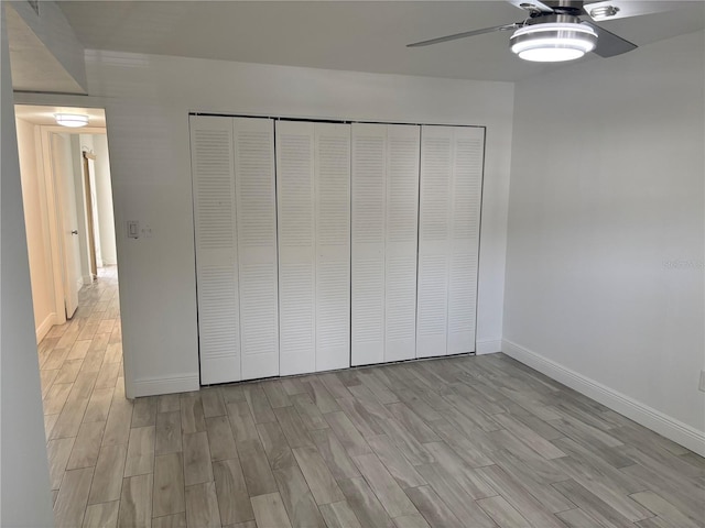 unfurnished bedroom featuring baseboards, light wood-style floors, a closet, and a ceiling fan