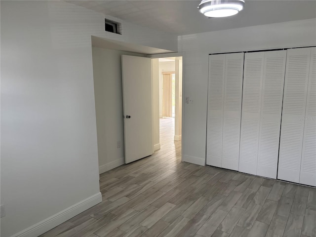 unfurnished bedroom with light wood finished floors, a closet, and baseboards