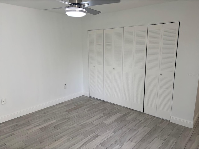 unfurnished bedroom featuring a closet, light wood-type flooring, baseboards, and ceiling fan