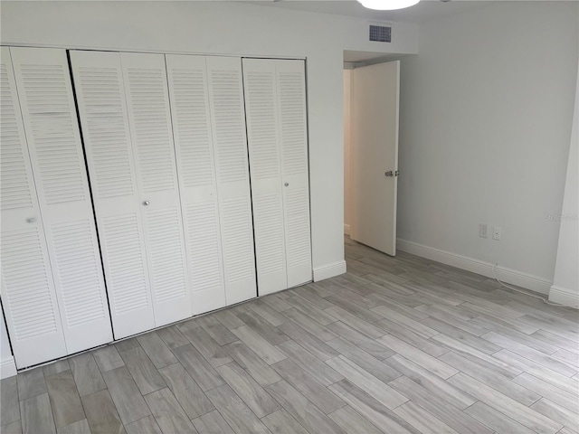 unfurnished bedroom with baseboards, light wood-style floors, a closet, and visible vents