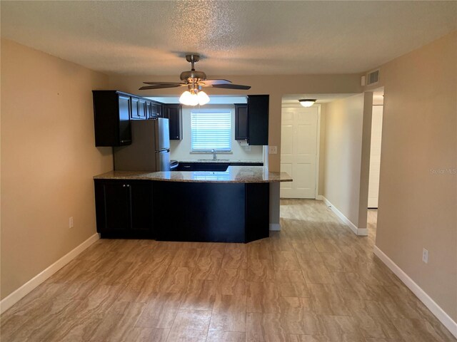 205 46th Avenue Terrace W Unit 425, Bradenton, FL 34207 - kitchen with a sink, freestanding refrigerator, ceiling fan, light stone countertops, and a peninsula