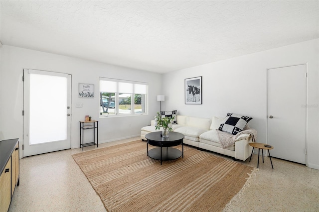 living area with a textured ceiling, baseboards, and light speckled floor