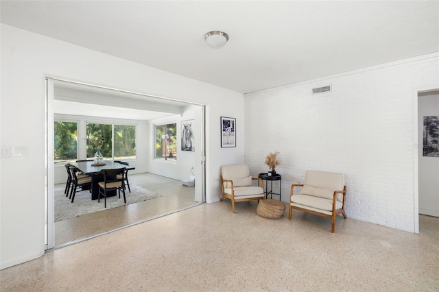 sitting room with speckled floor, visible vents, and brick wall