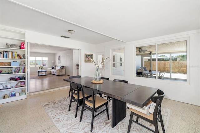 dining space with speckled floor, visible vents, and a ceiling fan