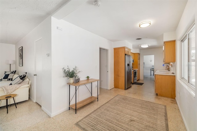 corridor with a sink, baseboards, visible vents, and light speckled floor