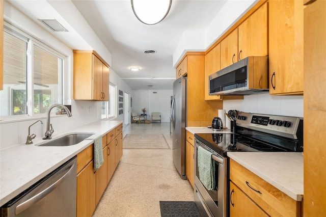 kitchen with light countertops, appliances with stainless steel finishes, a sink, and visible vents