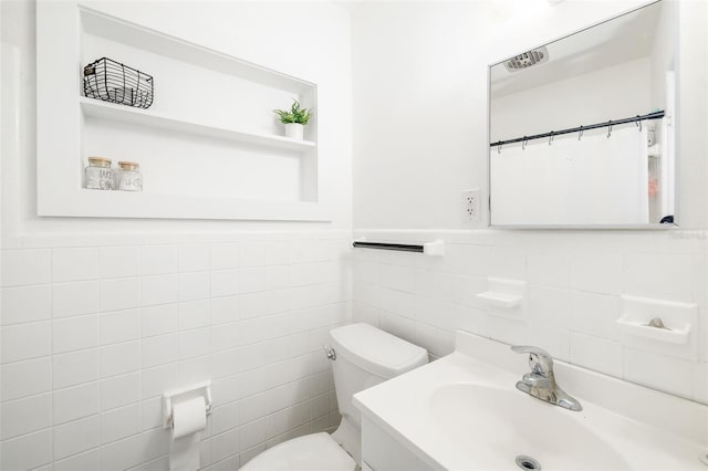 bathroom featuring a wainscoted wall, vanity, toilet, and tile walls