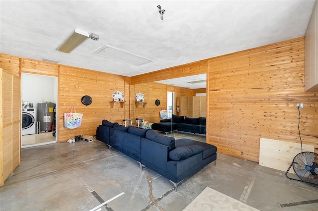 living room featuring electric water heater, wood walls, finished concrete flooring, and washer / clothes dryer