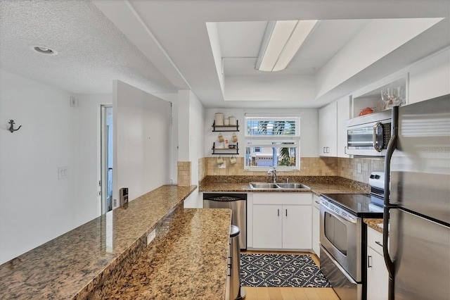 kitchen featuring white cabinets, a sink, tasteful backsplash, open shelves, and appliances with stainless steel finishes