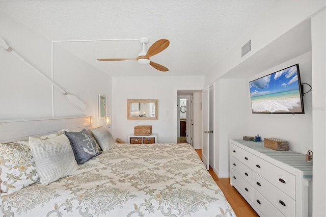 bedroom with a ceiling fan, visible vents, and light wood-style flooring