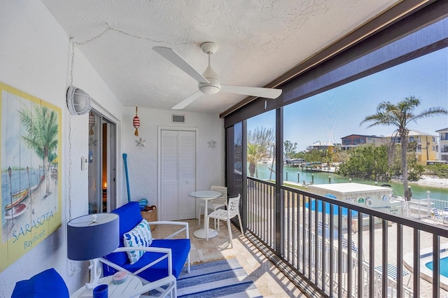 balcony with a water view, a ceiling fan, and visible vents