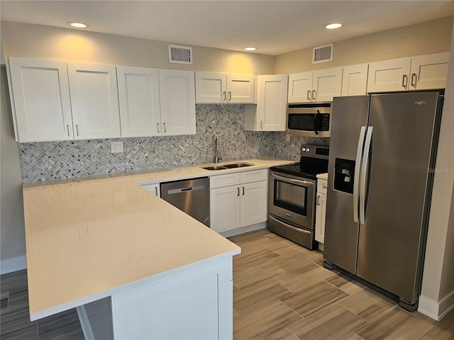 1654 Blakemore Ln, Sarasota, FL 34231 - kitchen with appliances with stainless steel finishes, a sink, a peninsula, white cabinets, and light countertops