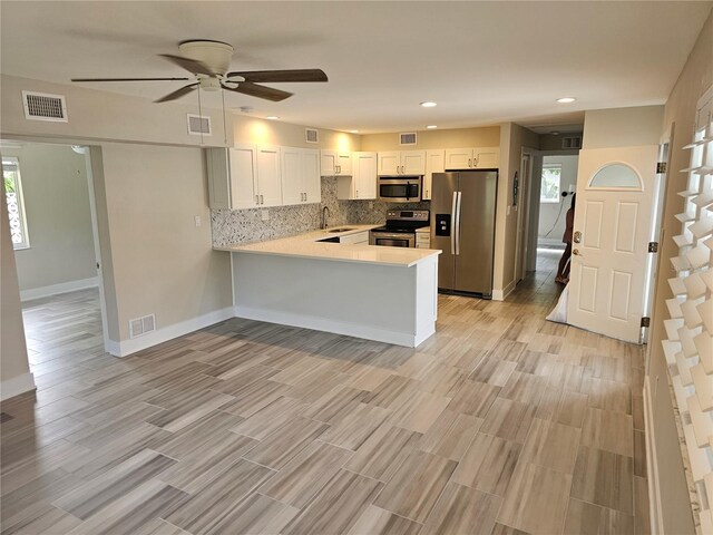 1654 Blakemore Ln, Sarasota, FL 34231 - kitchen with appliances with stainless steel finishes, a sink, a peninsula, light countertops, and white cabinetry