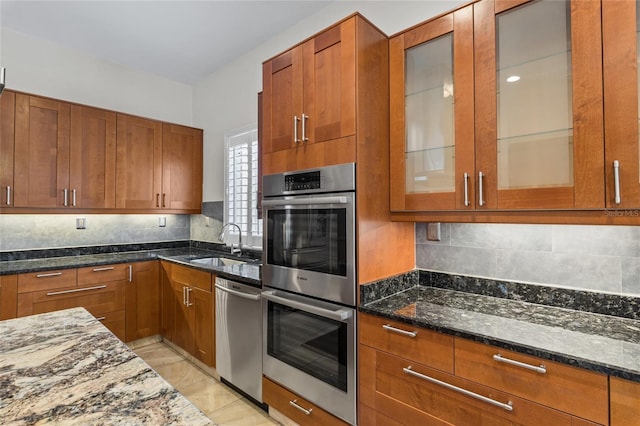 1828 Mova St, Sarasota, FL 34231 - kitchen with appliances with stainless steel finishes, a sink, dark stone countertops, brown cabinets, and backsplash