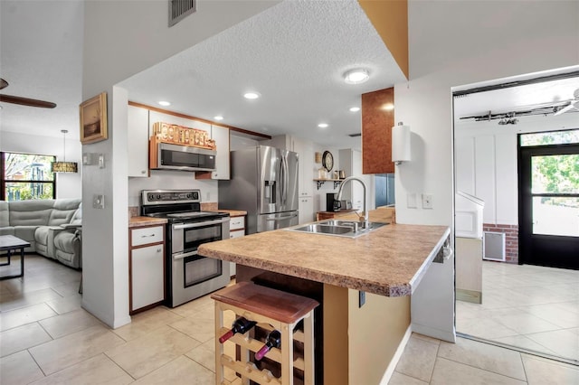 9011 Hilolo Ln, Venice, FL 34293 - kitchen featuring a peninsula, a textured ceiling, a kitchen bar, stainless steel appliances, and a sink