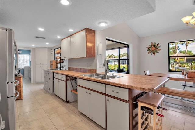 9011 Hilolo Ln, Venice, FL 34293 - kitchen with white cabinets, a sink, light countertops, appliances with stainless steel finishes, and a peninsula
