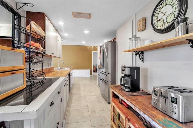 9011 Hilolo Ln, Venice, FL 34293 - kitchen with a sink, light countertops, freestanding refrigerator, a textured ceiling, and white cabinetry