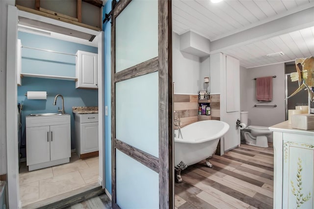 9011 Hilolo Ln, Venice, FL 34293 - full bathroom featuring a freestanding tub, toilet, beam ceiling, vanity, and wood finished floors