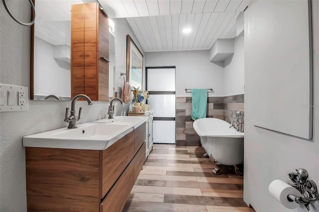 9011 Hilolo Ln, Venice, FL 34293 - bathroom featuring a sink, double vanity, a freestanding tub, and wood finished floors