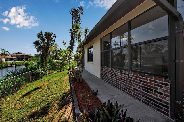 9011 Hilolo Ln, Venice, FL 34293 - view of home's exterior with a water view, a yard, brick siding, and fence