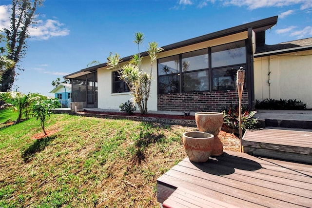 9011 Hilolo Ln, Venice, FL 34293 - rear view of property with a deck, stucco siding, a sunroom, and a lawn