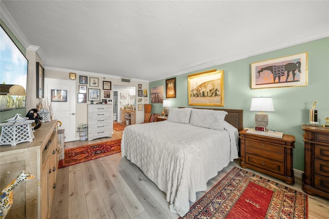 bedroom featuring crown molding, light wood finished floors, and visible vents
