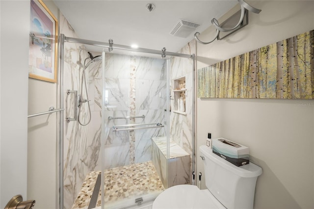 bathroom with a marble finish shower, visible vents, and toilet