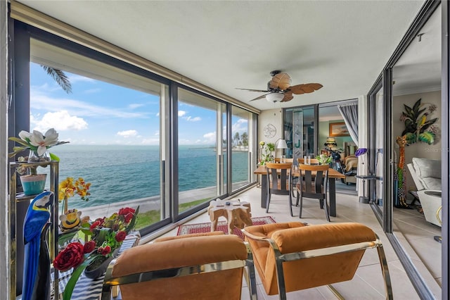 sunroom / solarium featuring a water view, tile patterned flooring, and a wall of windows