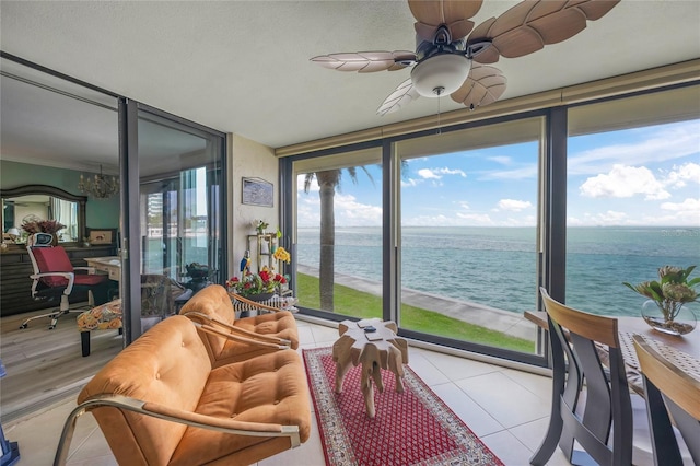 sunroom featuring a notable chandelier, floor to ceiling windows, a water view, and tile patterned flooring