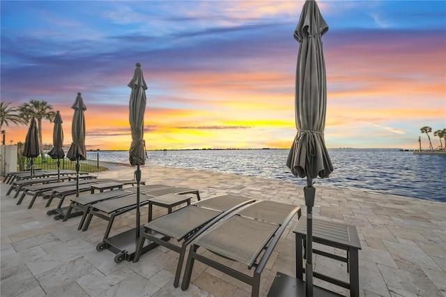 surrounding community with a view of the beach, a water view, and a patio area