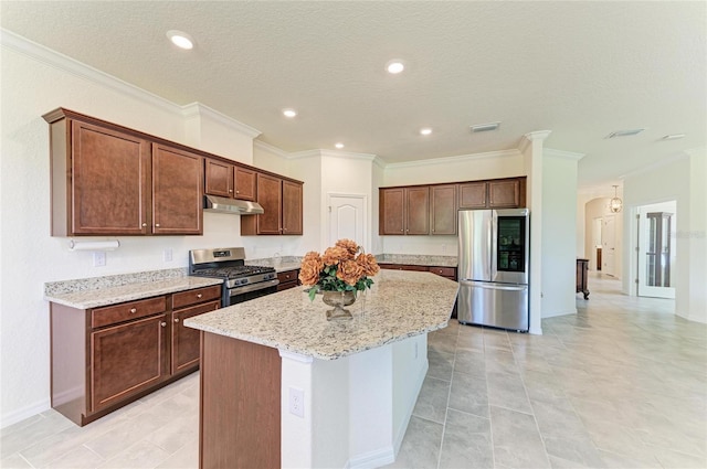kitchen with under cabinet range hood, stainless steel appliances, visible vents, light stone countertops, and a kitchen island with sink