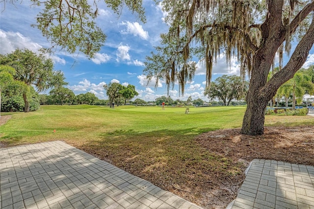 view of yard with view of golf course and a patio