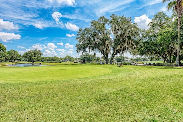 surrounding community with golf course view, a yard, and a water view