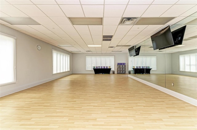 workout area featuring baseboards, wood finished floors, visible vents, and plenty of natural light