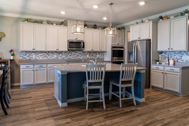 11702 Tetrafin Dr, Riverview, FL 33579 - kitchen featuring appliances with stainless steel finishes, crown molding, backsplash, a kitchen island with sink, and white cabinetry
