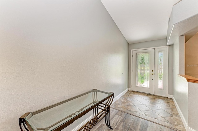 foyer entrance with baseboards, a textured wall, and light wood-type flooring
