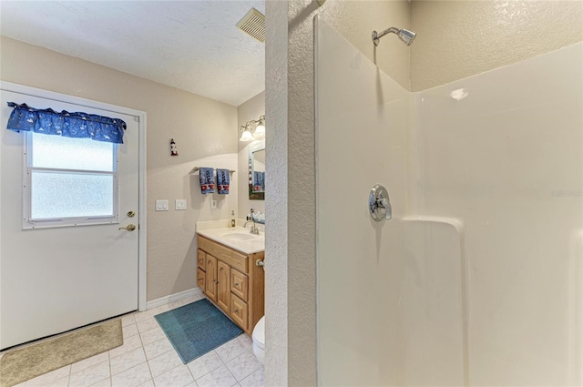 bathroom with a textured wall, tile patterned flooring, vanity, a shower, and visible vents