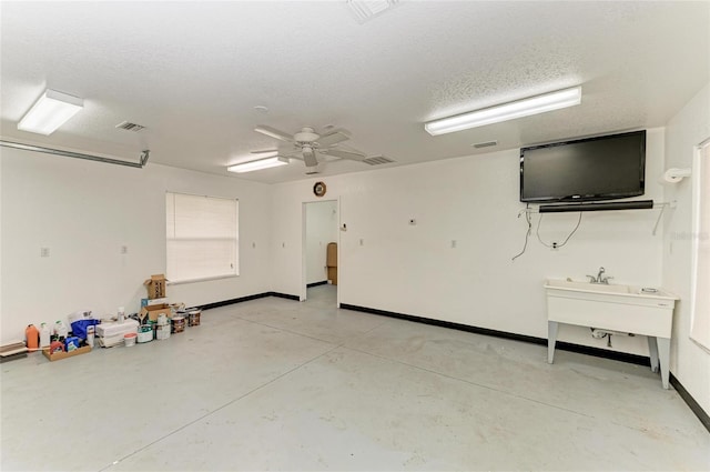 garage featuring a sink, baseboards, a ceiling fan, and visible vents