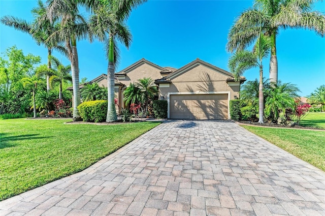 view of front of house featuring decorative driveway, stucco siding, an attached garage, and a front lawn