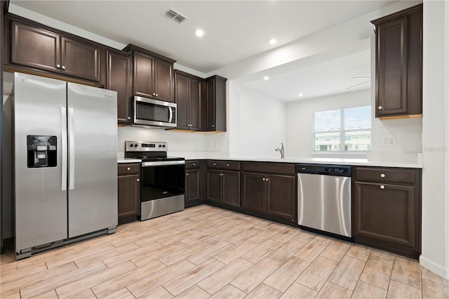 5543 Pleasantview Ct, Bradenton, FL 34211 - kitchen with light countertops, stainless steel appliances, dark brown cabinetry, and light wood-style floors