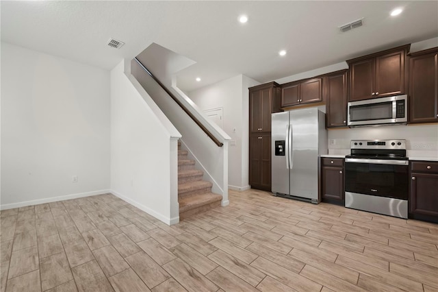 5543 Pleasantview Ct, Bradenton, FL 34211 - kitchen with visible vents, dark brown cabinets, wood tiled floor, light countertops, and stainless steel appliances