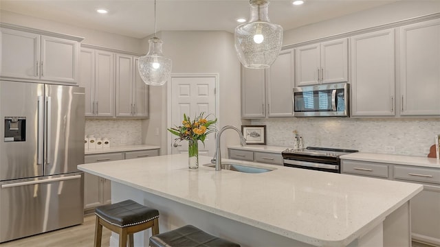8110 Trimbelle Ter, Parrish, FL 34219 - kitchen featuring appliances with stainless steel finishes, decorative backsplash, a kitchen breakfast bar, a kitchen island with sink, and light stone countertops