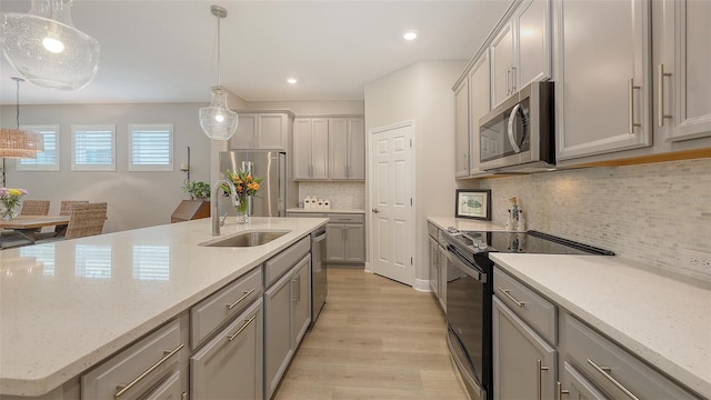 8110 Trimbelle Ter, Parrish, FL 34219 - kitchen featuring stainless steel appliances, light wood-type flooring, an island with sink, decorative light fixtures, and recessed lighting