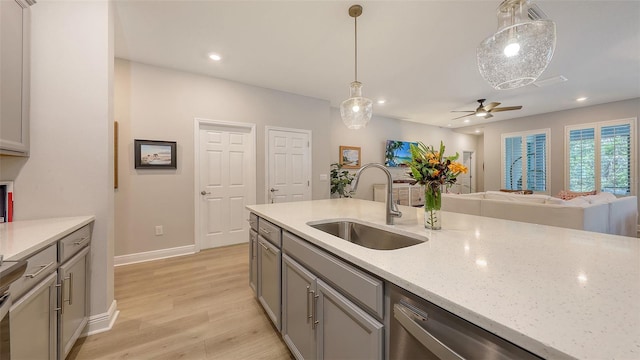 8110 Trimbelle Ter, Parrish, FL 34219 - kitchen featuring light wood finished floors, gray cabinets, decorative light fixtures, ceiling fan, and light stone counters