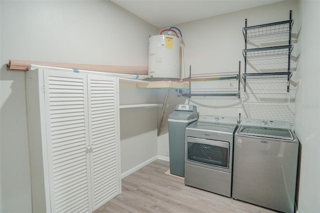 clothes washing area with water heater, laundry area, light wood-style floors, baseboards, and washer and dryer