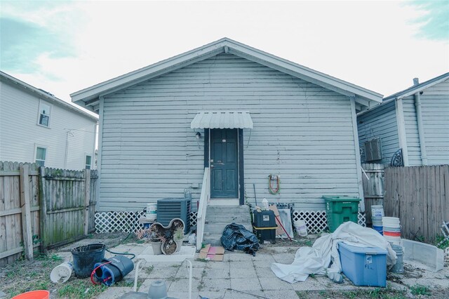 rear view of house featuring central air condition unit, entry steps, and a fenced backyard
