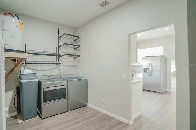 laundry room with light wood-style floors, visible vents, washing machine and clothes dryer, and laundry area