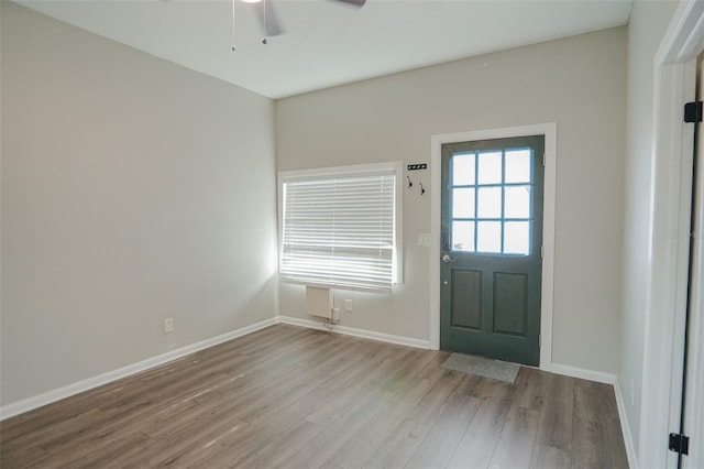 doorway to outside with wood finished floors, a ceiling fan, and baseboards