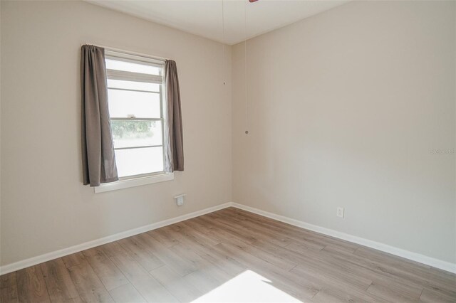 spare room with baseboards and light wood-style floors